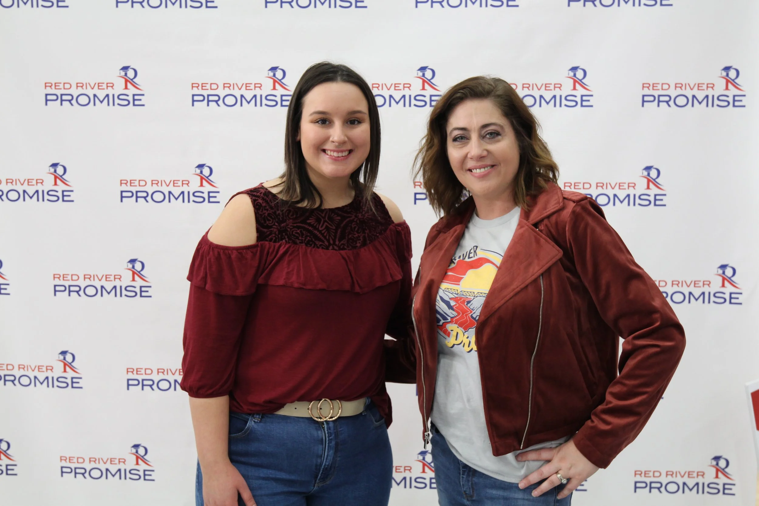Student and NCTC employee posing in front of backdrop at a Red River Promise pep rally